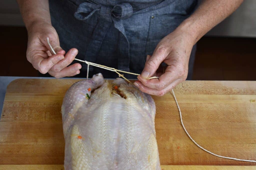 thread being tied around the chicken legs.