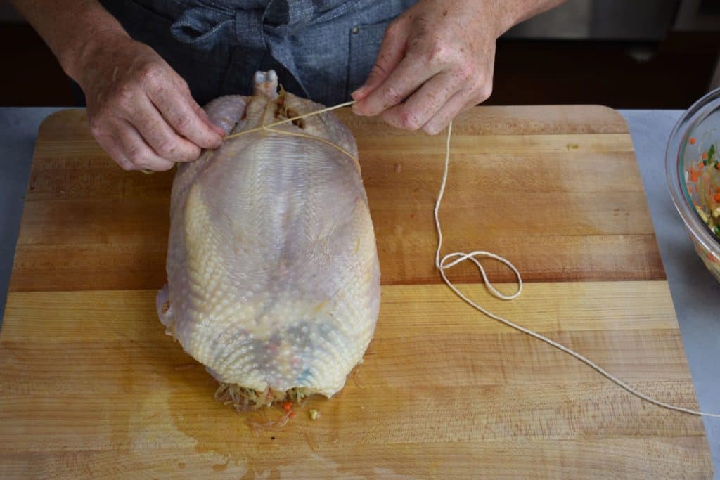 a knot being tied around the stuffed chicken.