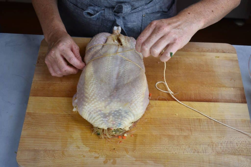 more string being wrapped around the chicken and tied to keep the stuffing in.