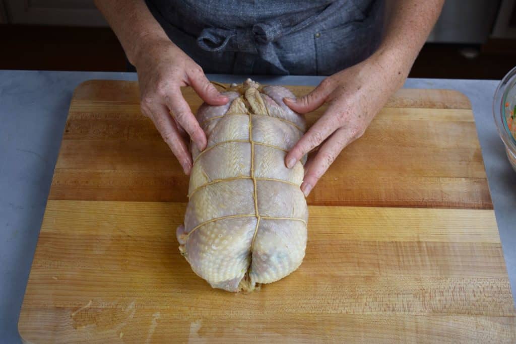 the fully tied Japanese stuffed chicken on a chopping board.