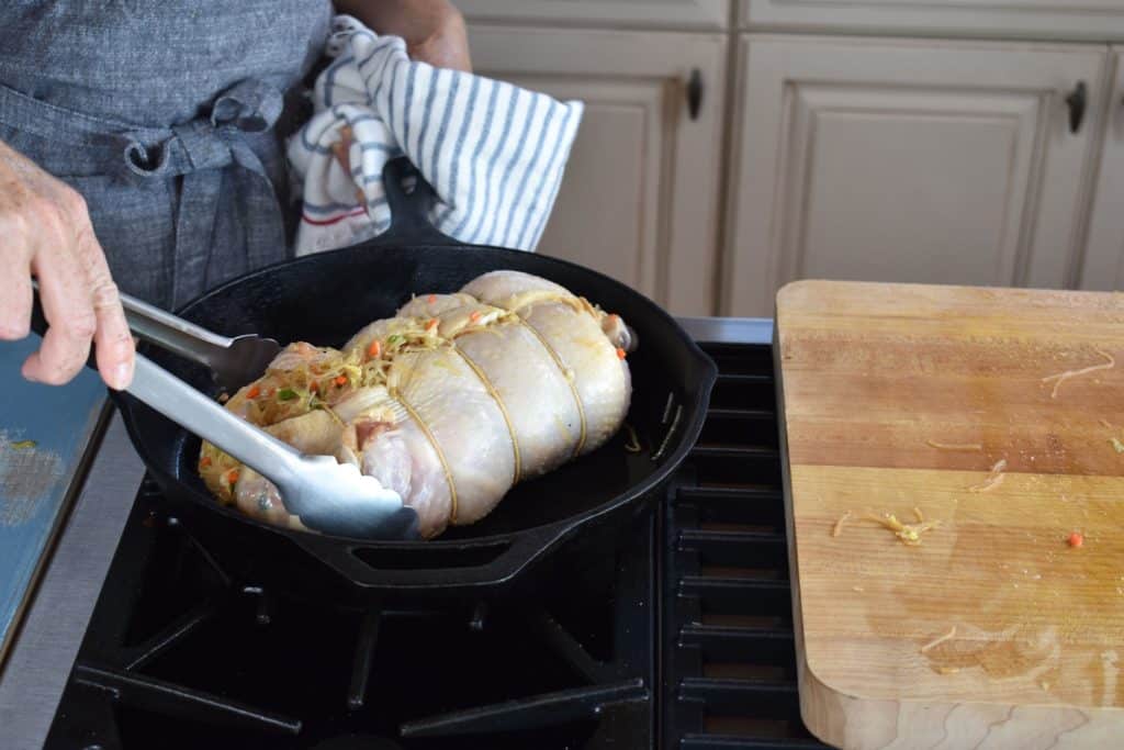 stuffed chicken in a skillet being seared.
