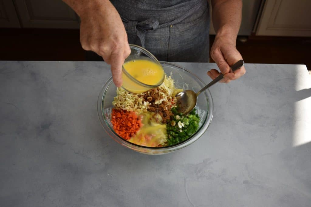 whisked egg being poured into the stuffing ingredients.