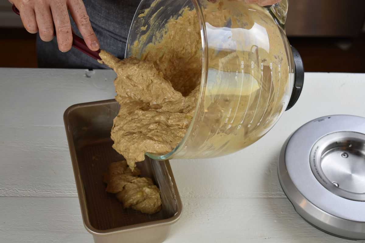 batter being scraped into a loaf pan