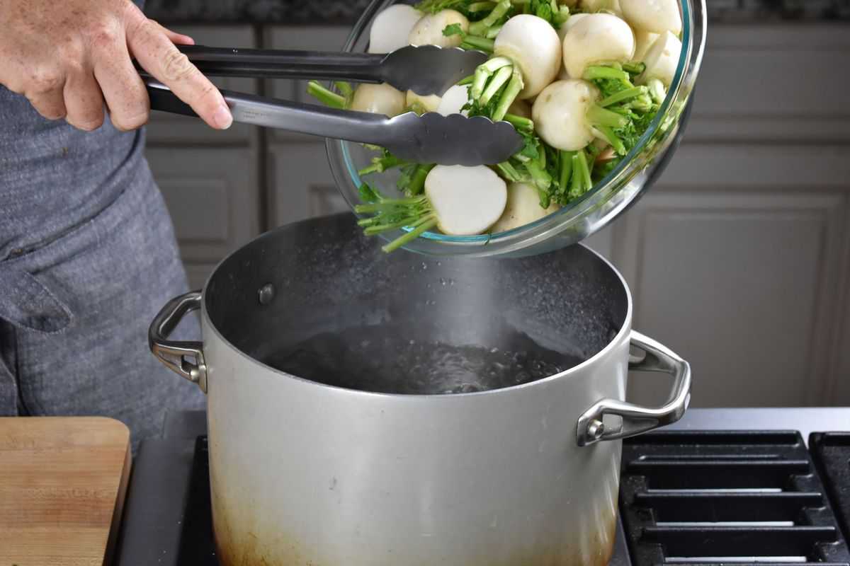 chopped turnips being placed into a pot of boiling water.