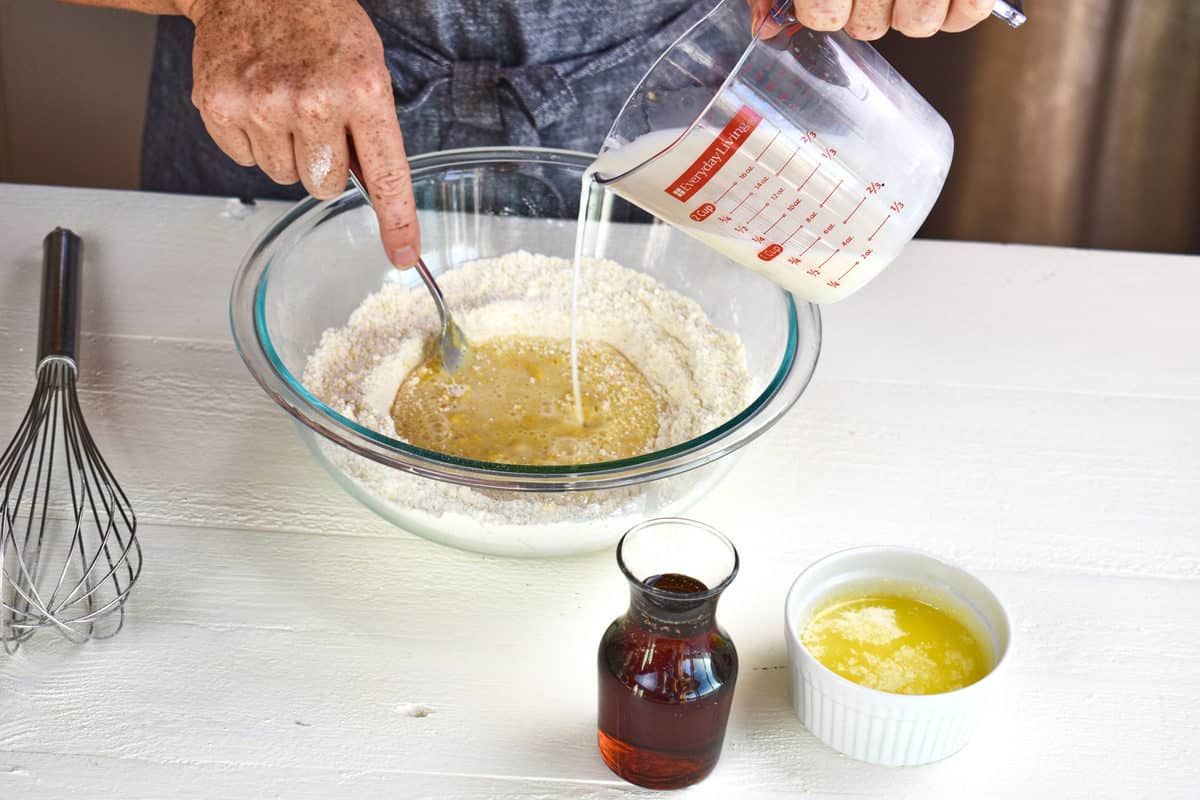 milk being added to the dry ingredients for maple cornbread muffins.