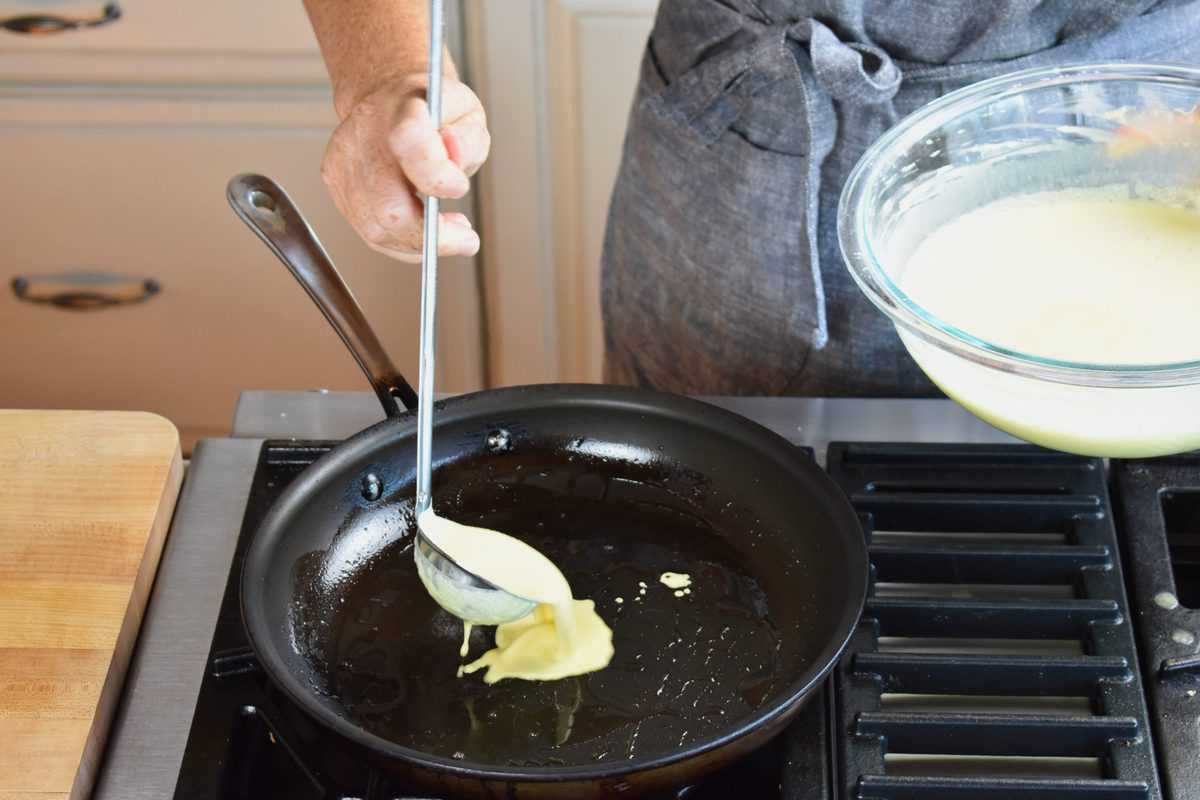 batter being ladled into a heated skillet.