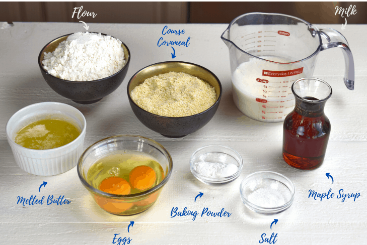 ingredients in bowls ready to make maple cornbread muffins: flour, cornmeal, milk, maple syrup, melted butter, eggs, baking powder and salt.