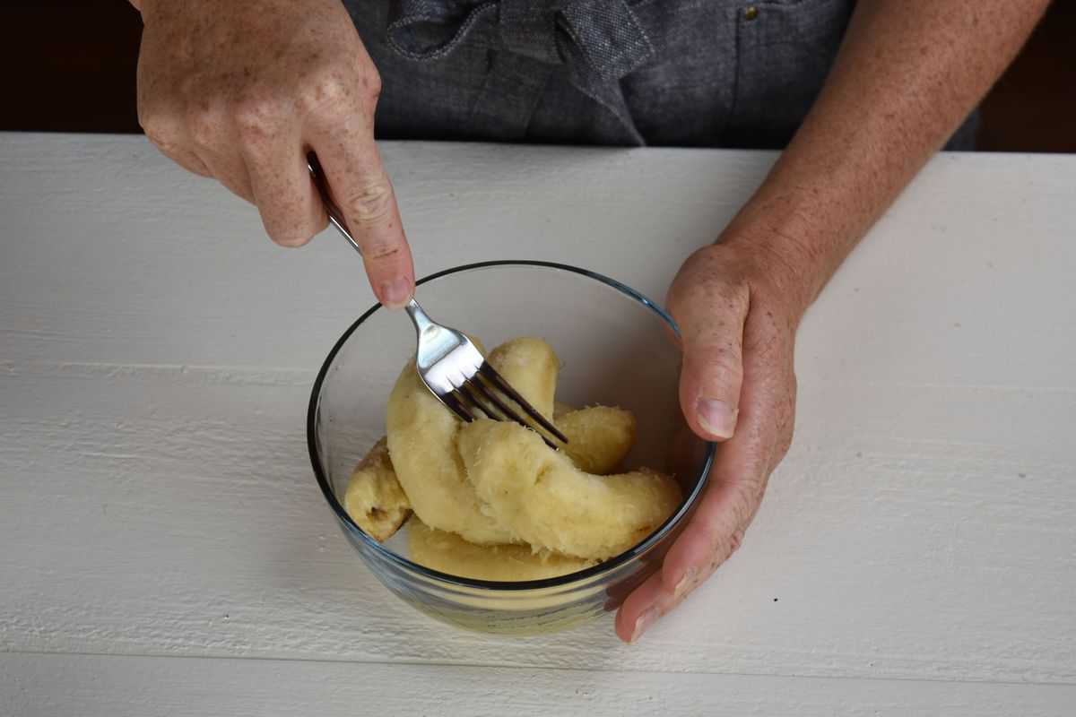 bananas being mashed in a bowl