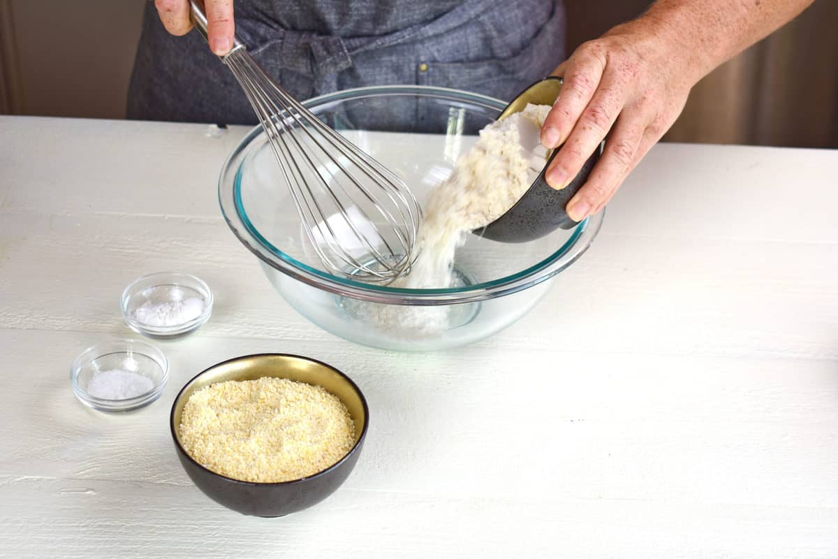 dry ingredients being mixed into a glass bowl with a whisk.