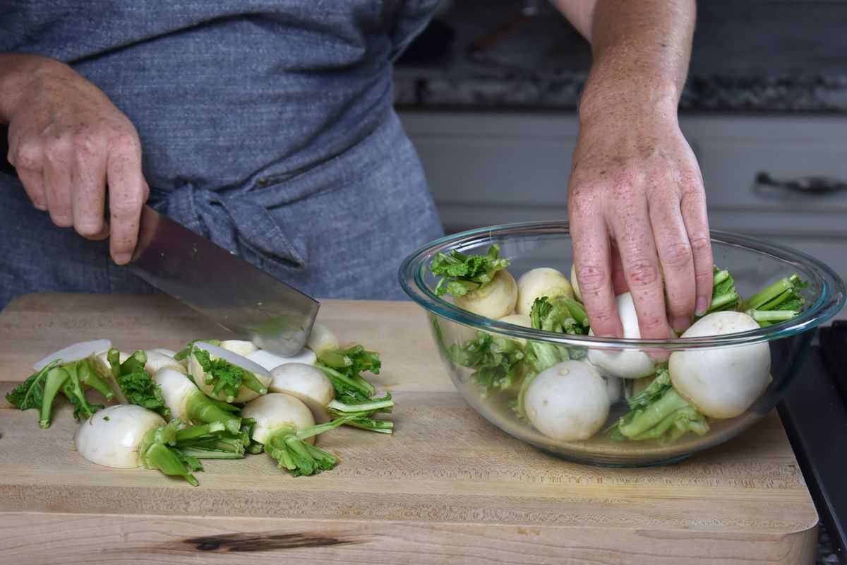 a bowl of Tokyo turnips and some turnips being chopped on a wooden chopping board.