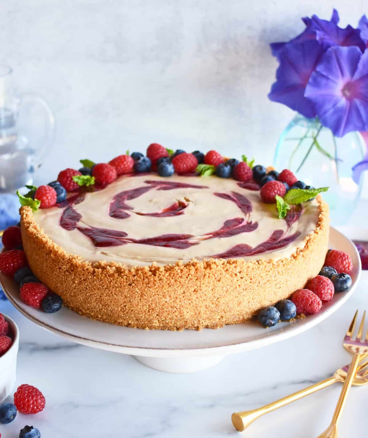 The finished no bake raspberry mascarpone cheesecake with a raspberry swirl and fresh fruit garnish.