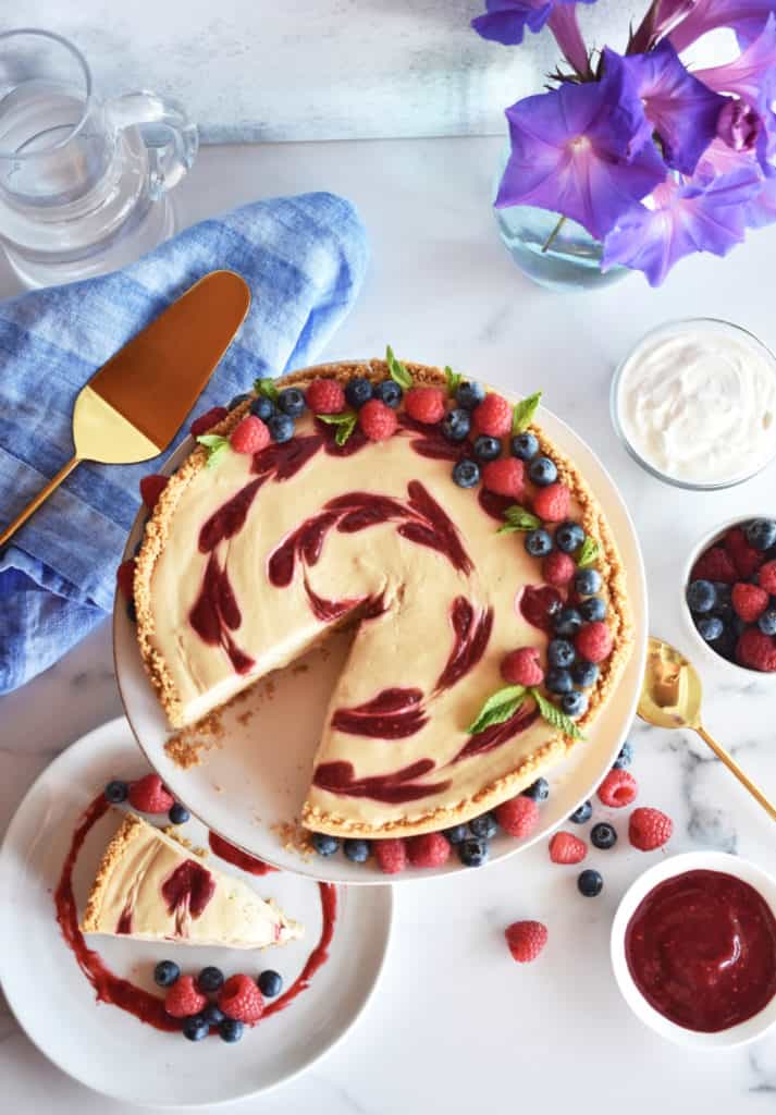 overhead shot of a raspberry cheesecake with a slice taken out of it and placed on a plate.