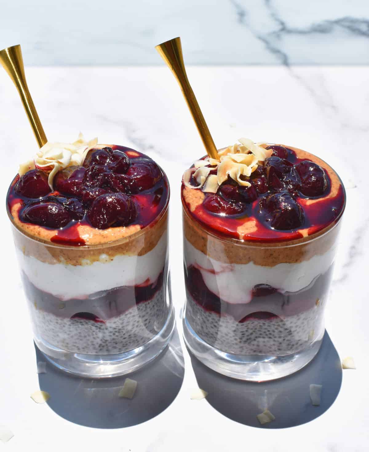 two coconut cherry chia pudding cups side by side with spoons