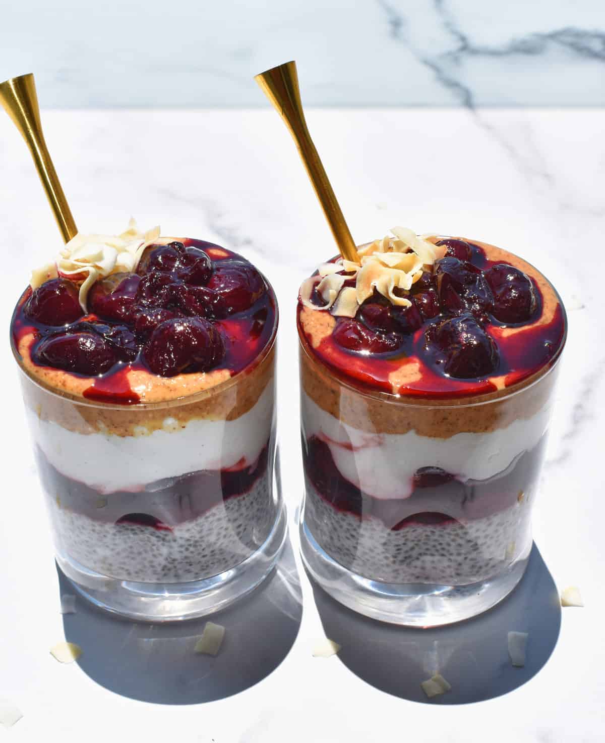 two coconut cherry chia pudding cups side by side with spoons