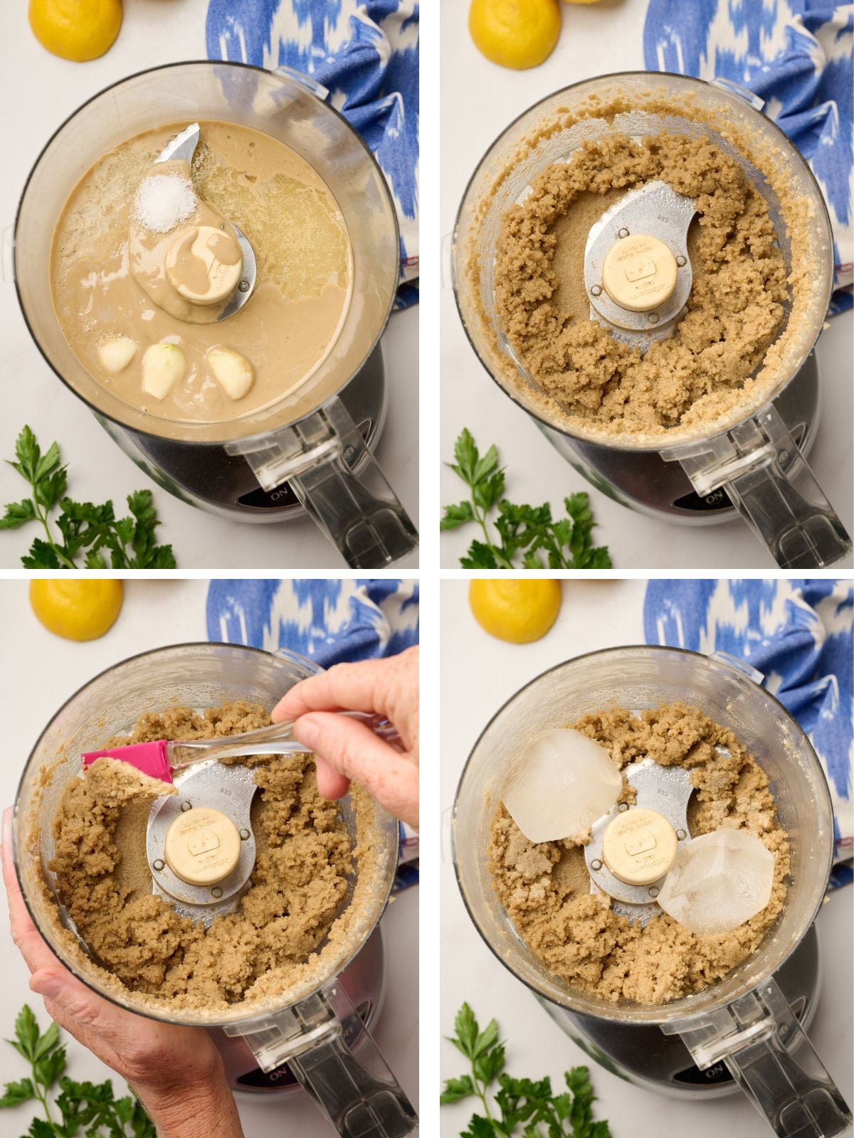 Tahini, garlic, salt, and lemon juice in a food processor, blended into a chunky base, ready to be processed into smooth and creamy tahini sauce. Fresh parsley, lemons, and ikat blue linen are in the background.