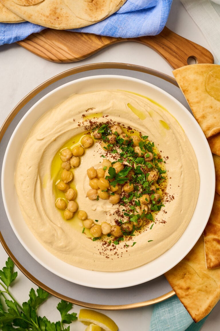 Close-up of creamy hummus garnished with chickpeas, sumac, olive oil, and parsley