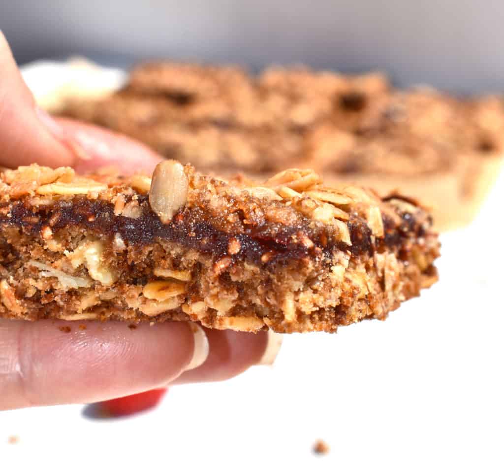 a slice of jammy raspberry oatmeal bar showing the jam filling