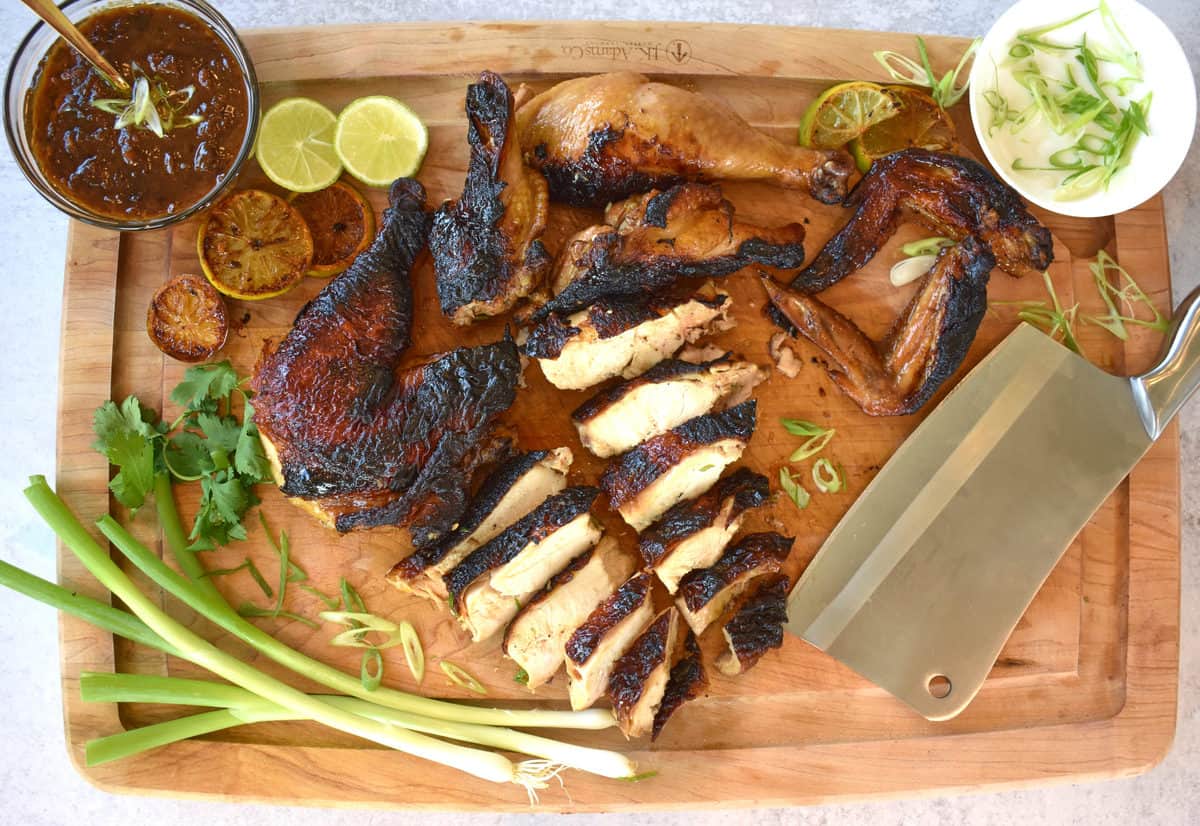 a chopping board with sliced roasted soy chicken and ingredients surrounding