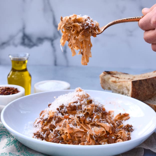 a bowl of pasta bolognese with a forkful of pasta in the shot