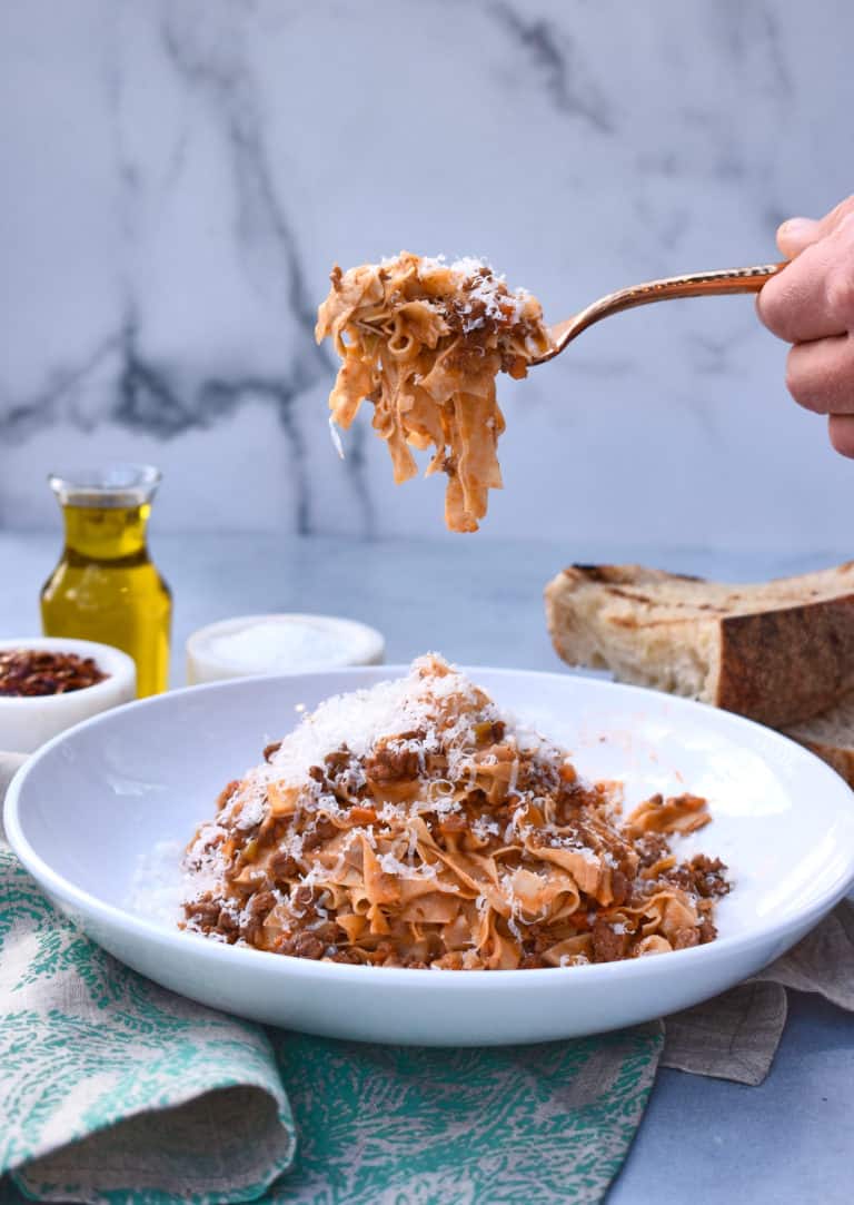 a bowl of pasta bolognese with a forkful of pasta in the shot