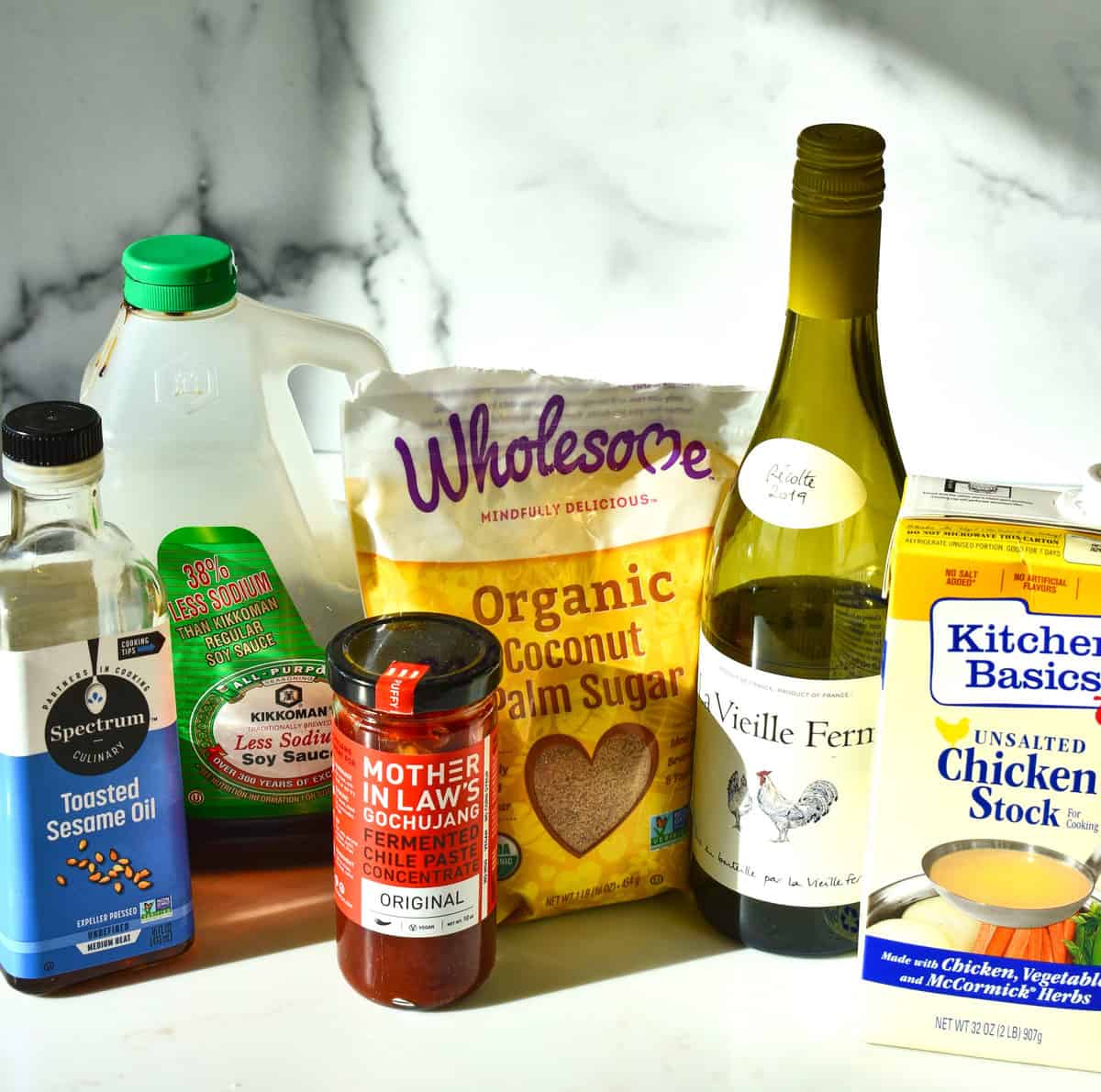 various ingredients ready to make braised beef: sesame oil, soy sauce, wine, coconut palm sugar and stock