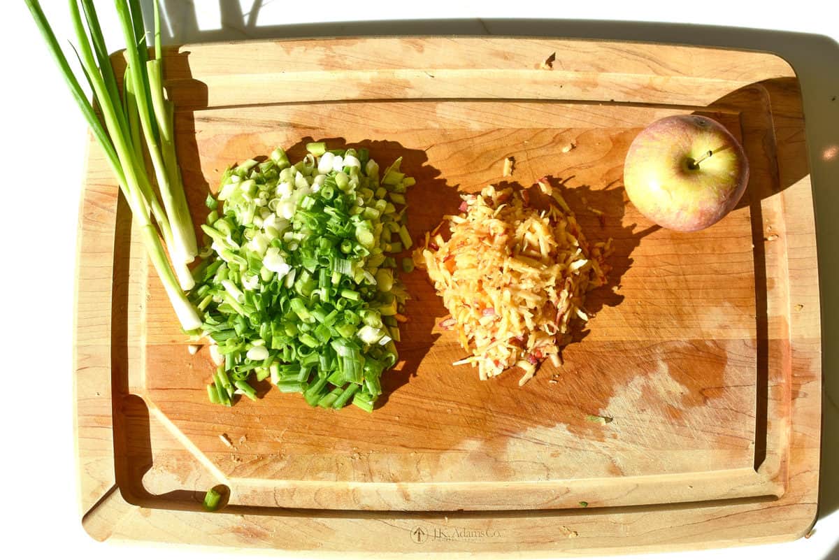 green onions chopped on a board with apple