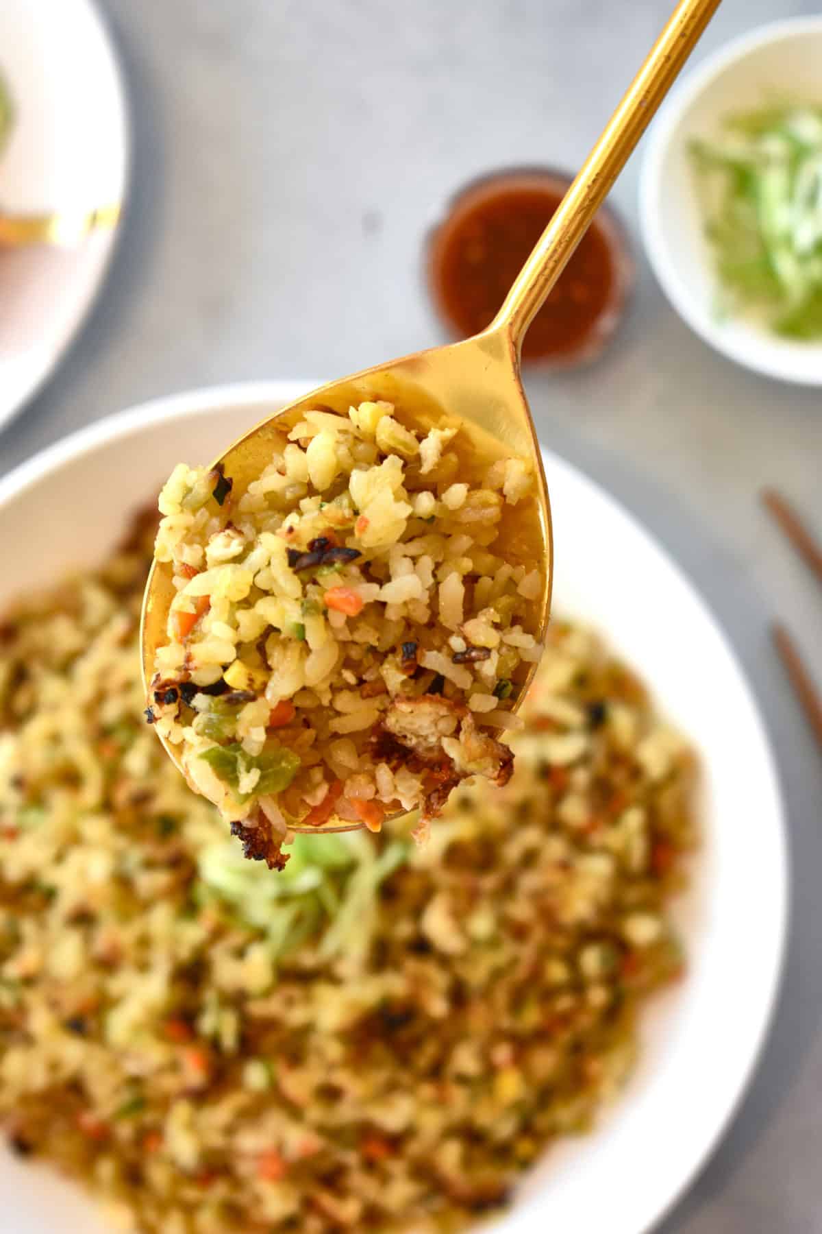 close up of a spoonful of vegetable rice with a dish full in the background