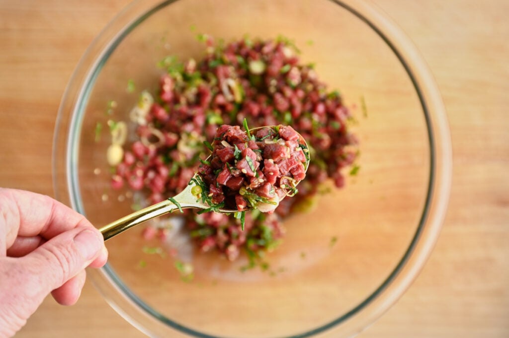 The finished Japanese steak tartare mixture in a bowl with a spoonful of mixture ready to serve.