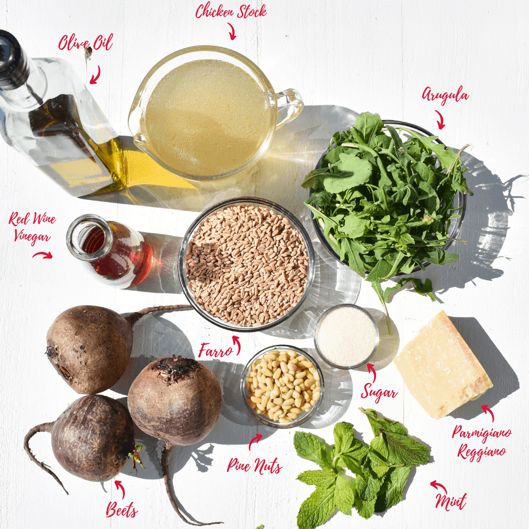 overhead shot of ingredients: olive oil, stock, arugula, red wine vinegar, farro, pine nuts, parmigiano reggiano, mint and beets