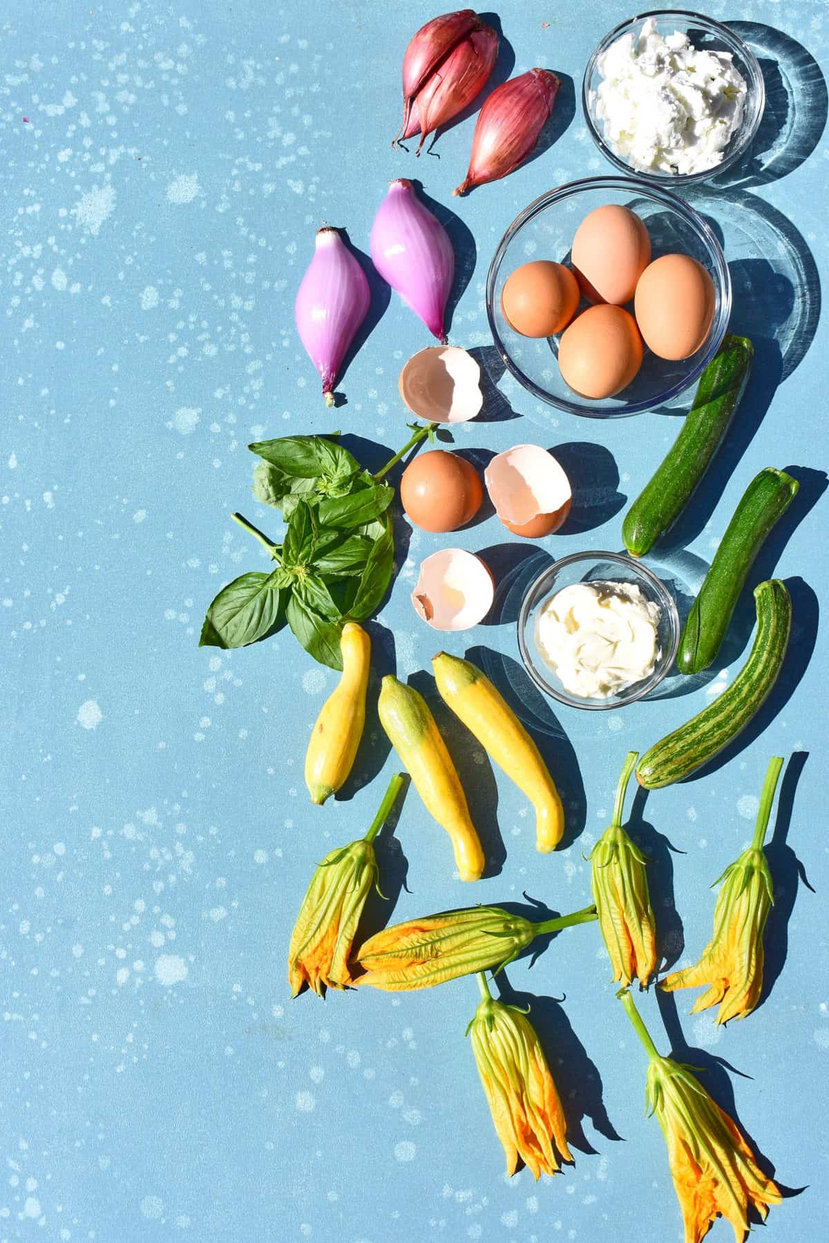 ingredients for frittata: shallots, eggs, goat cheese, squash blossoms and summer squash