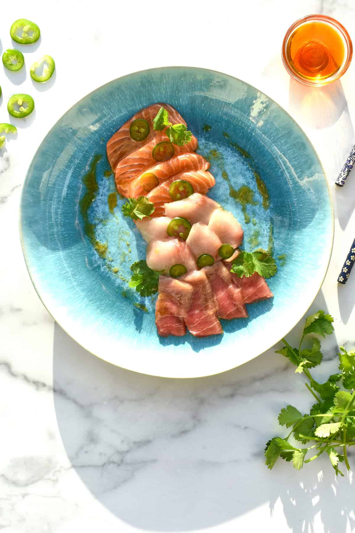 overhead shot of sashimi salmon with cilantro, jalapeno and chili oil in the background