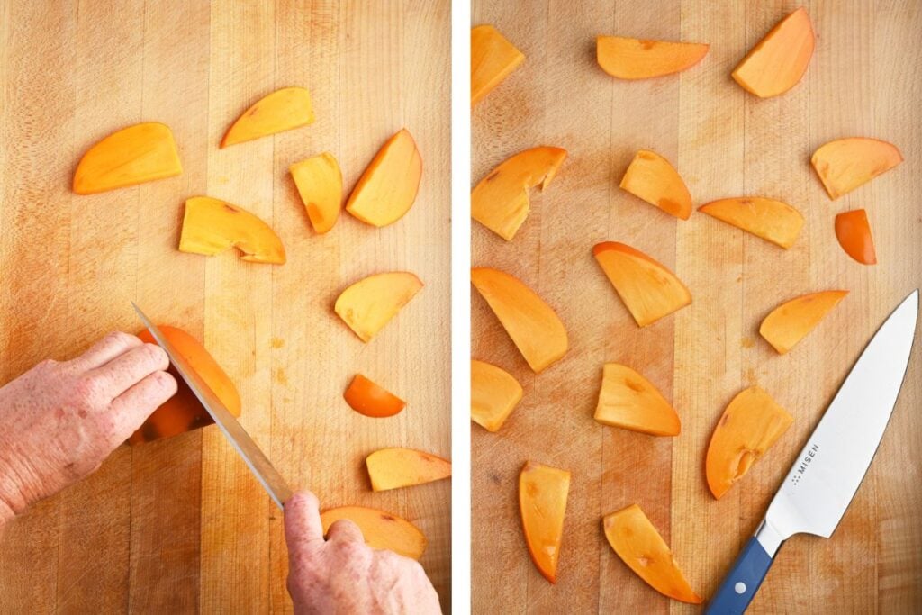 Hand slicing bright orange persimmons into wedges on a wooden cutting board.