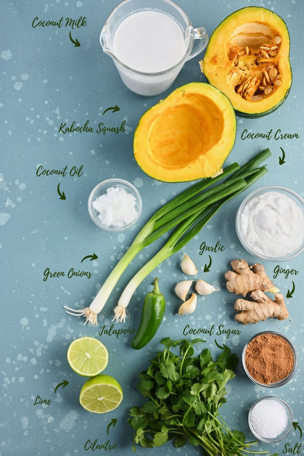 Ingredients for kabocha squash soup on a blue surface board, including squash, coconut milk, and other aromatics and ingredients.