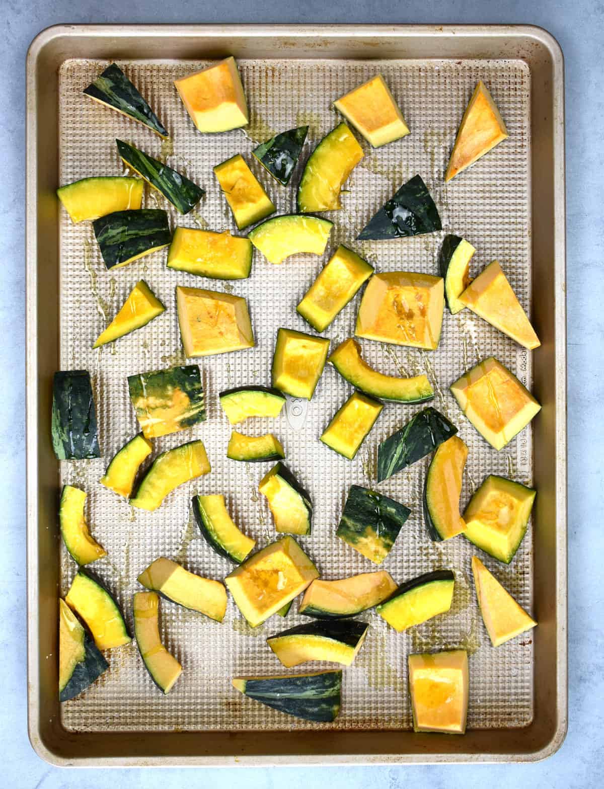 sliced kobocha squash on a pan ready to go in the oven