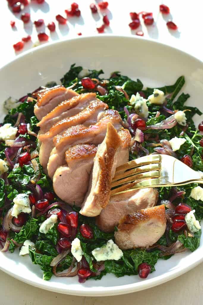 Sliced duck breast on a bed of green leaves