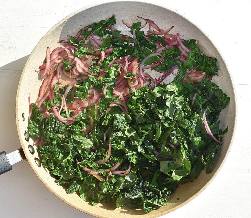 chopped kale and red onion in a pan
