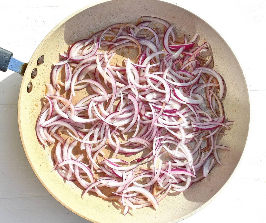 sliced red onions in a pan