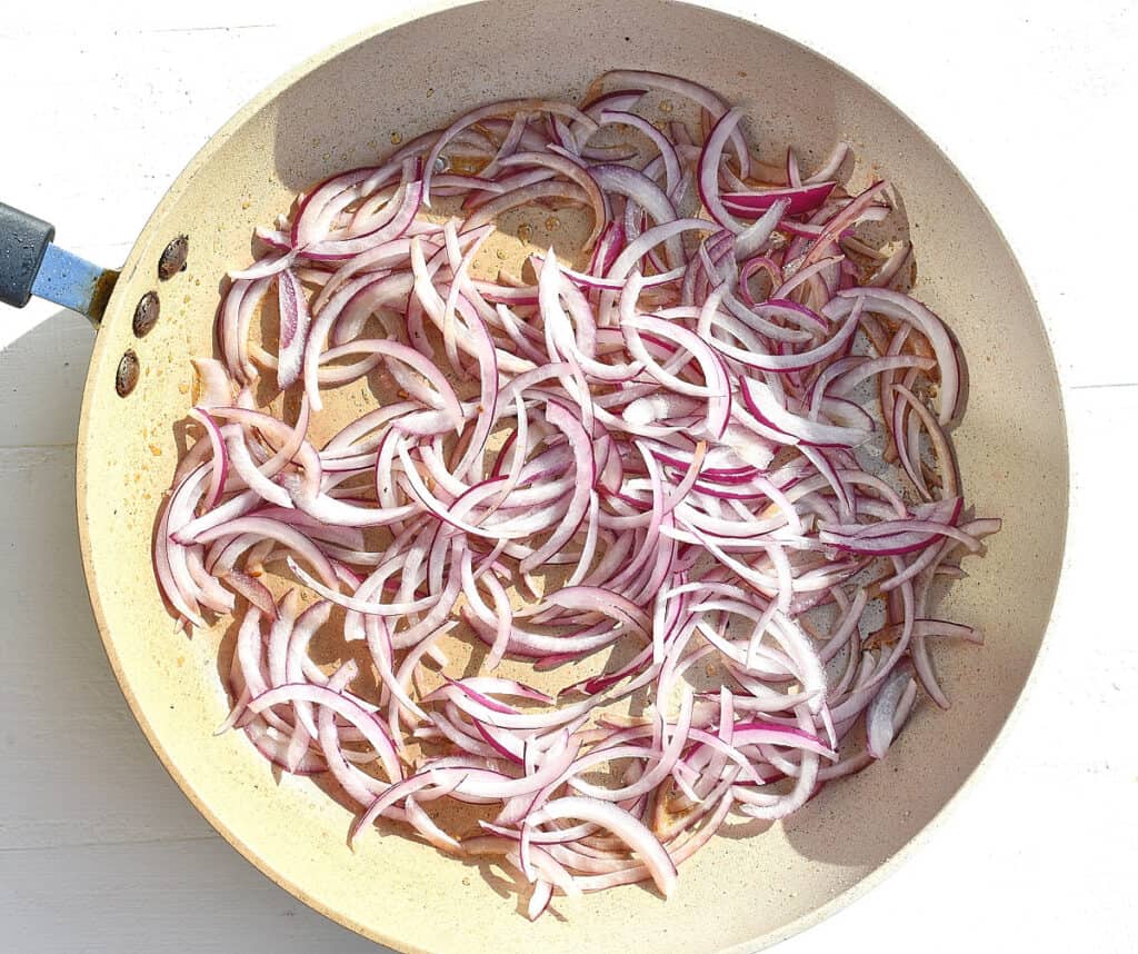 sliced red onions in a pan