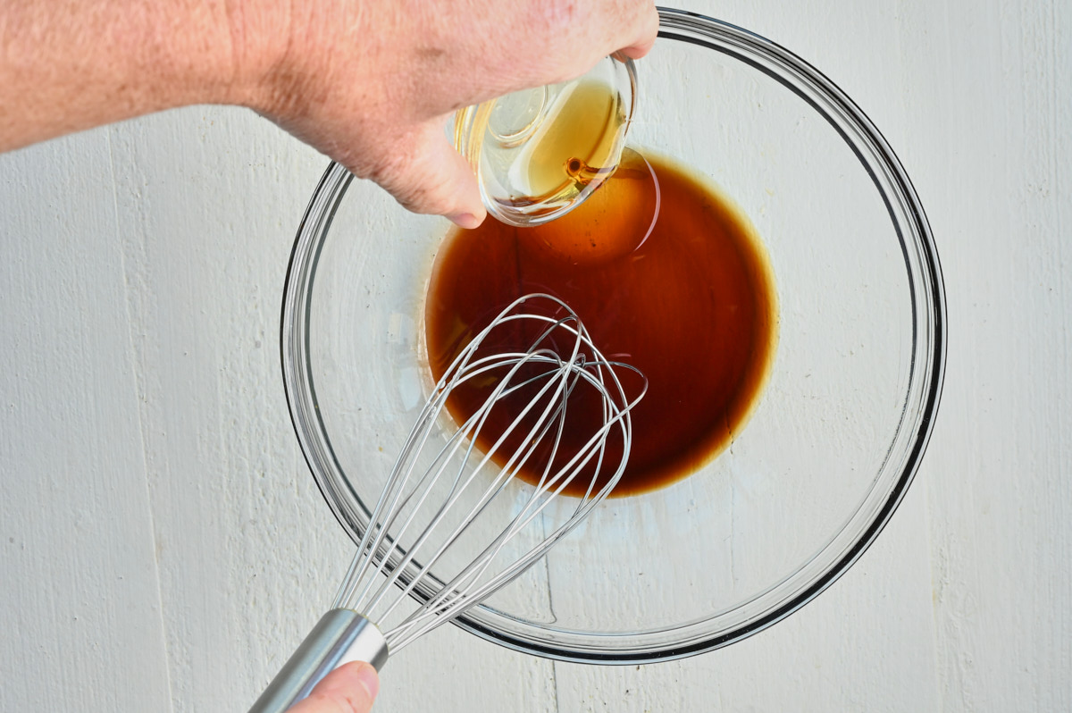 oil being added to soy sauce being ready to be whisked