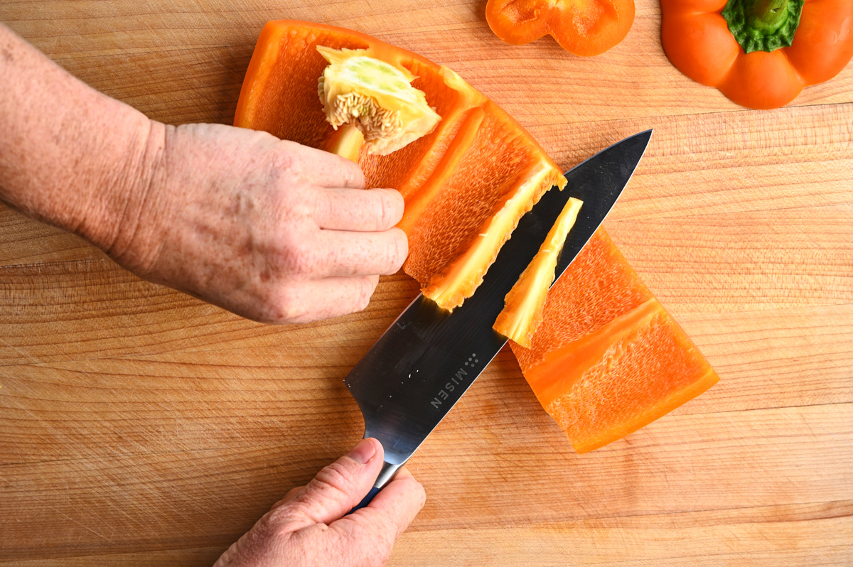 Hands finishing seeding an orange bell pepper