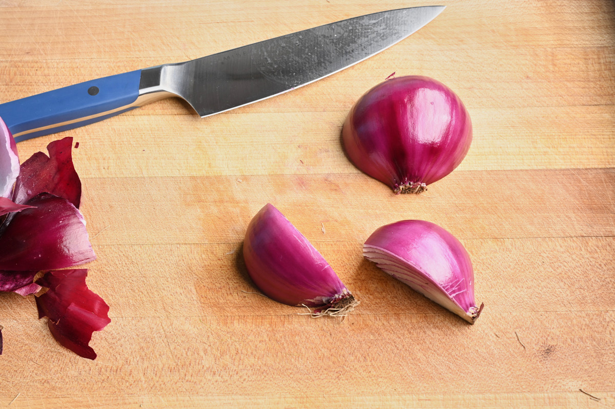 cut red onion on cutting board beside a knife