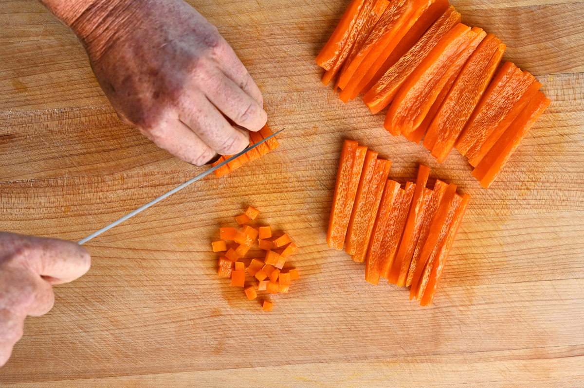 Orange Bell Peppers being diced against a wooden cutting board