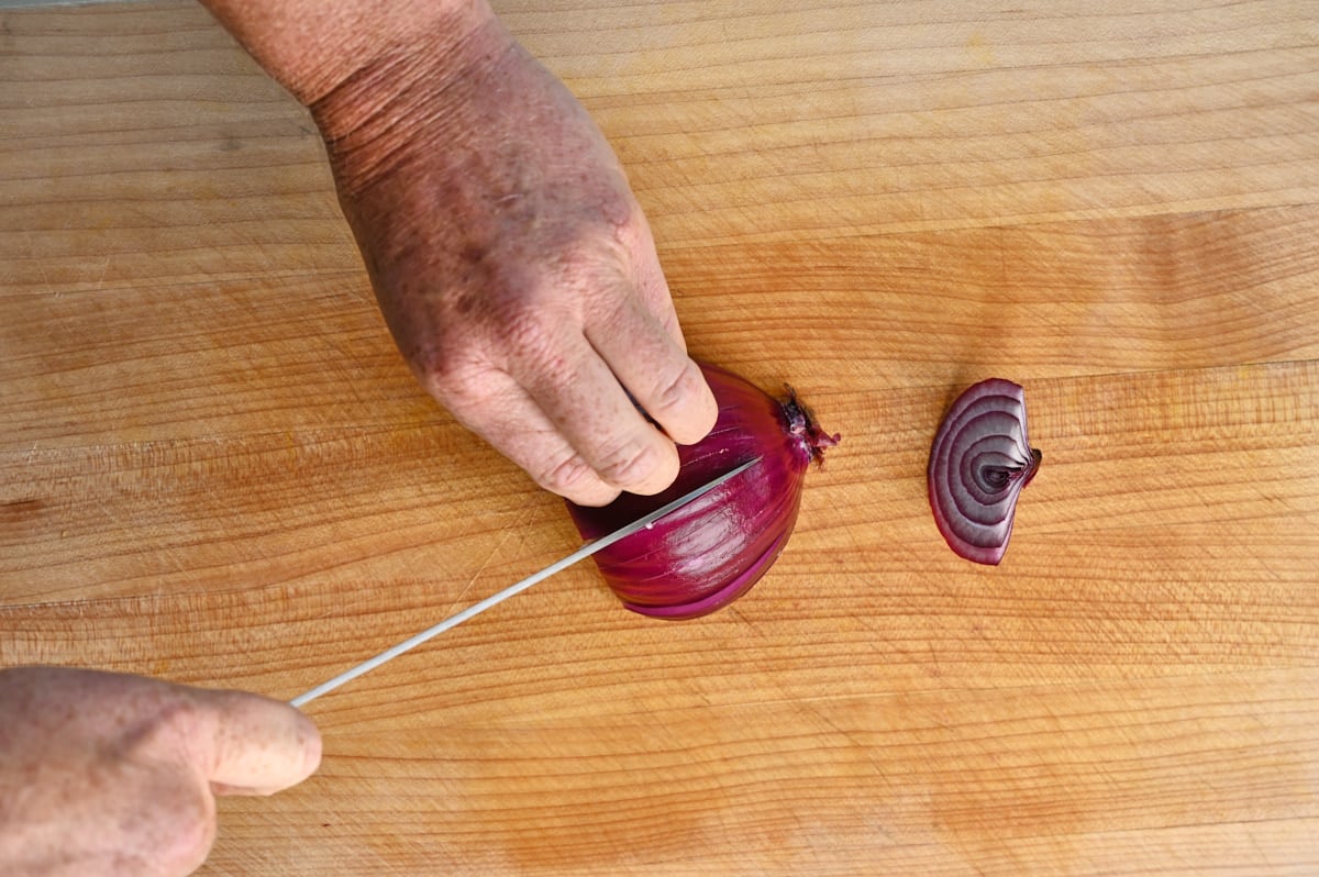 a halved red onion being sliced
