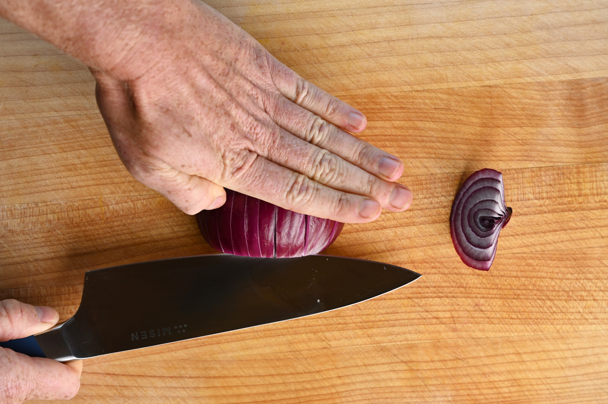 a red onion being sliced horizontally