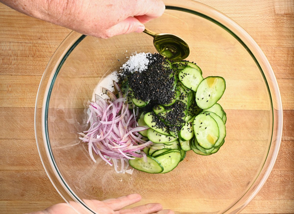 red onion, black sesame seeds, sliced cucumbers and salt in a glass bowl