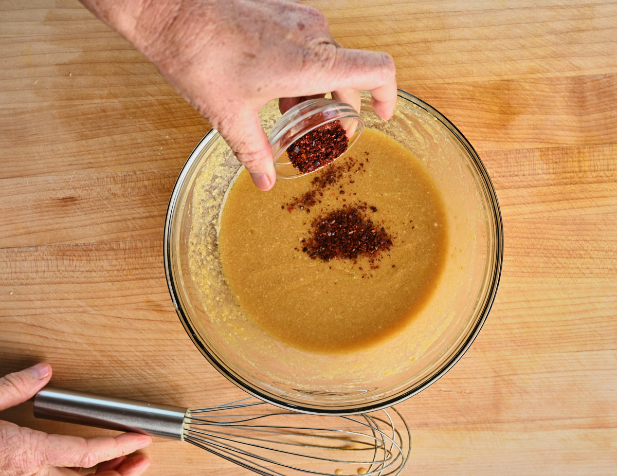 chilli flakes being added to the vinaigrette