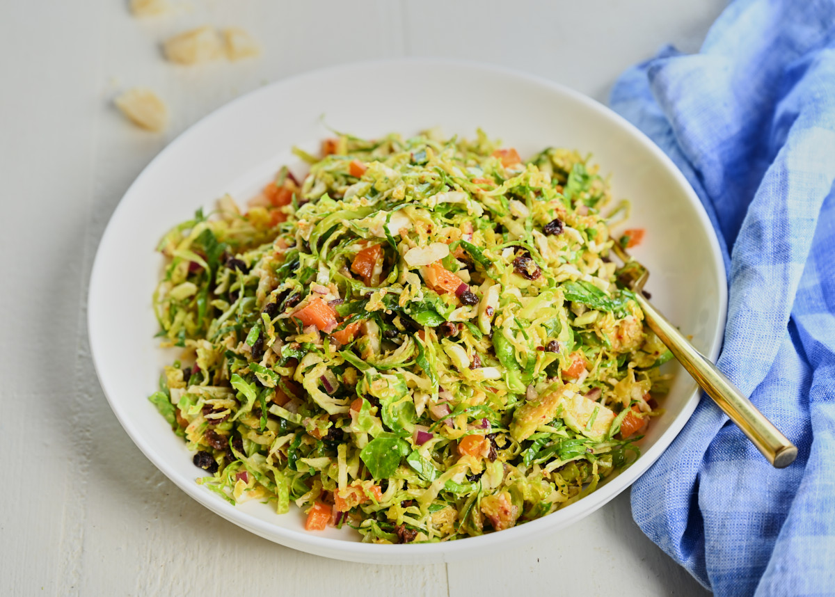 Shredded Brussel Sprout Salad with miso in a white bowl with a fork sticking in it