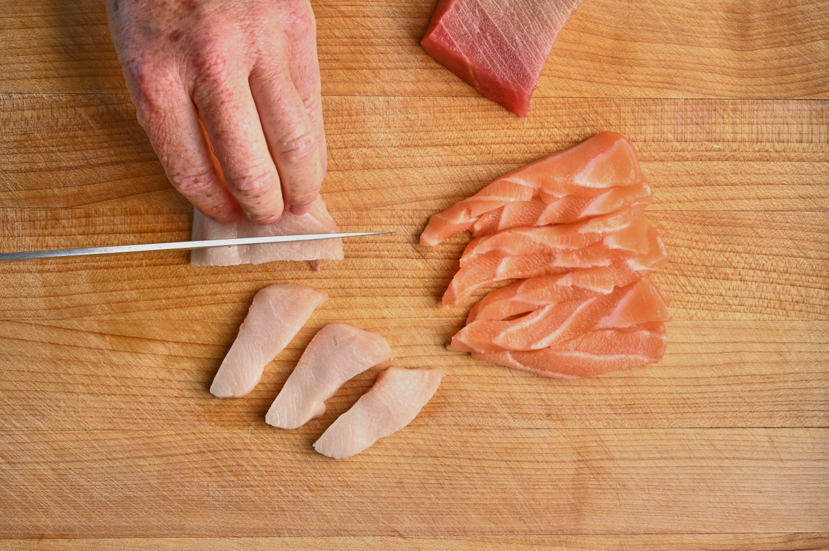 Woman cutting toro with sliced salmon beside