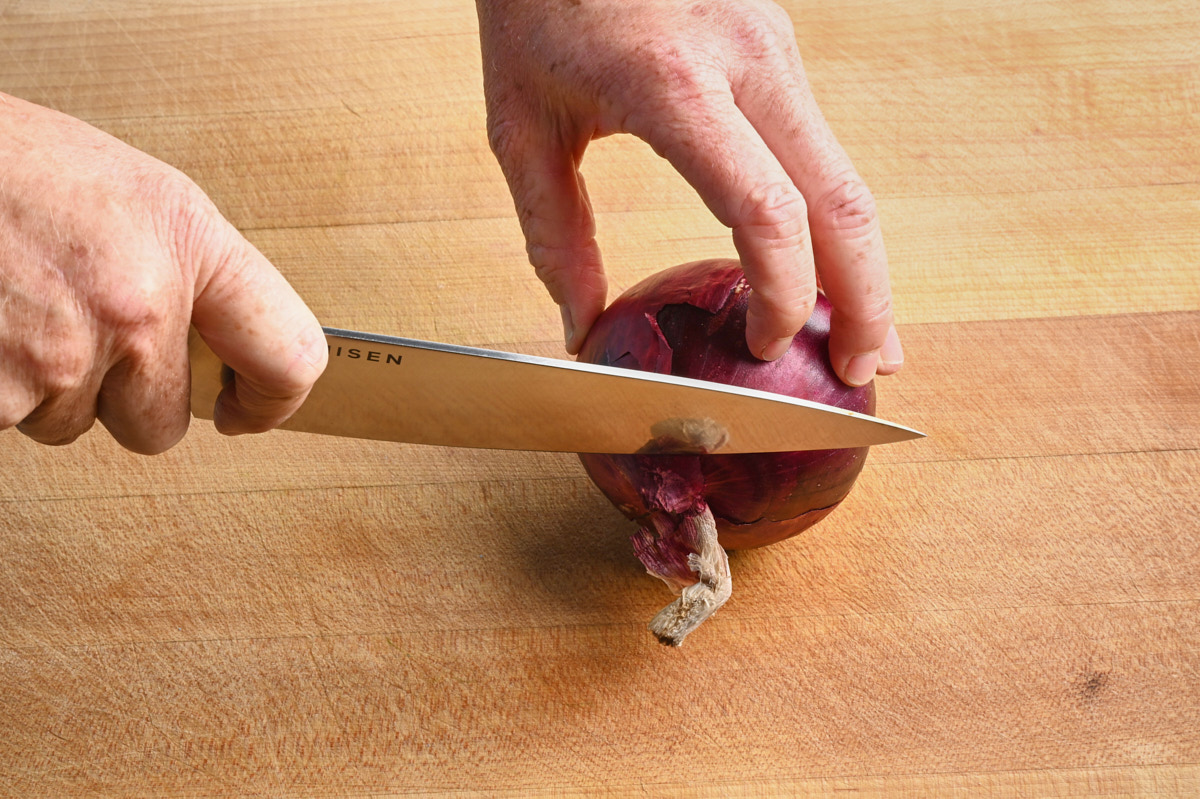 cutting the root off a red onion