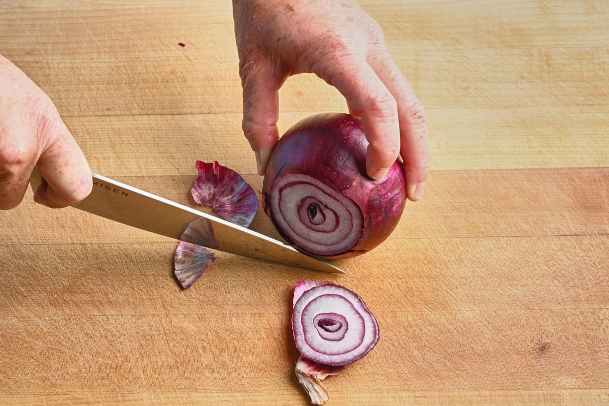 cutting the root off a red onion